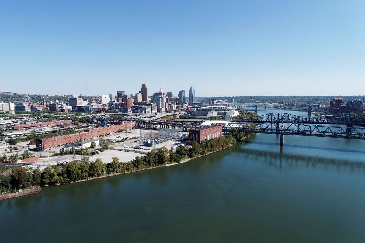 Wide view along the Ohio River toward the Cincinnati skyline, with a steel truss bridge spanning the water in the foreground.